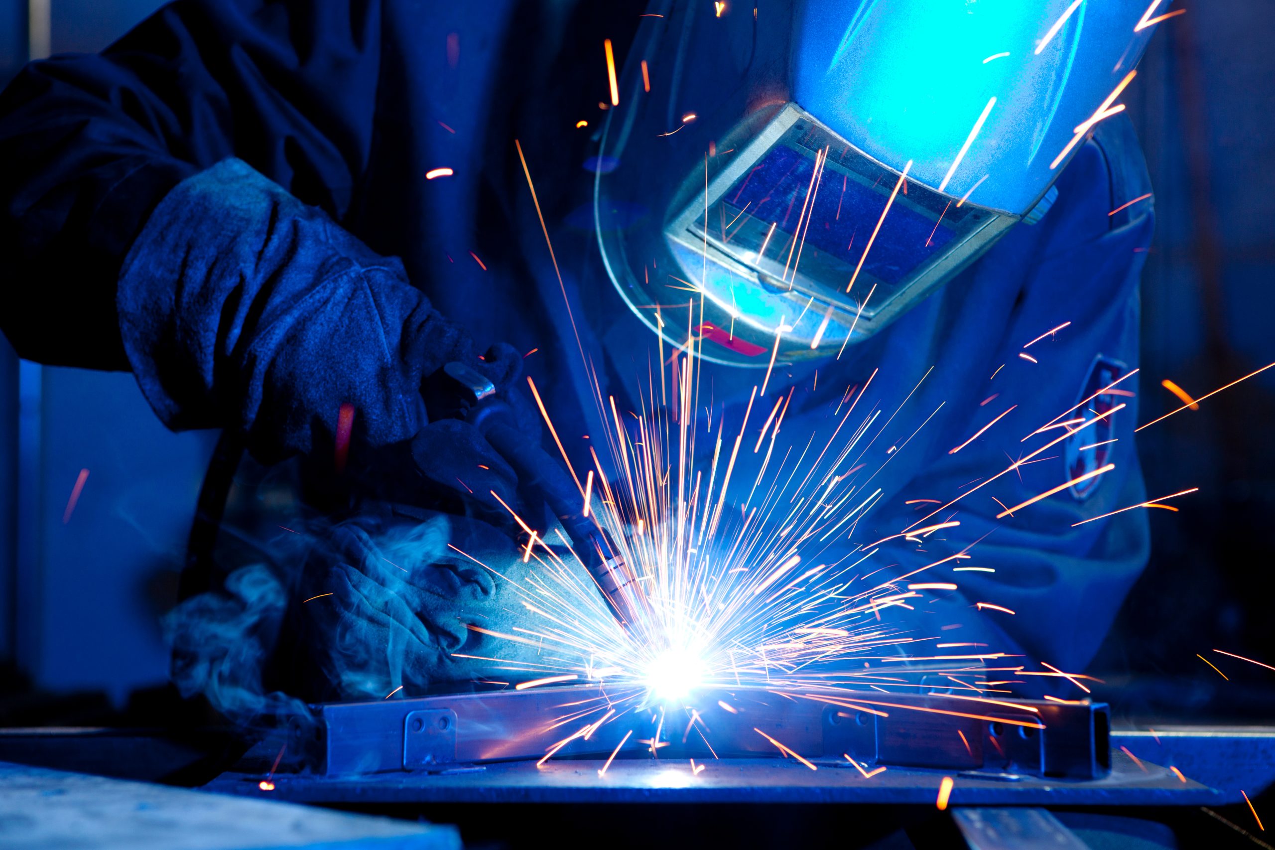 A person wearing protective gear welds metal, bright sparks flying as they work on their projects.